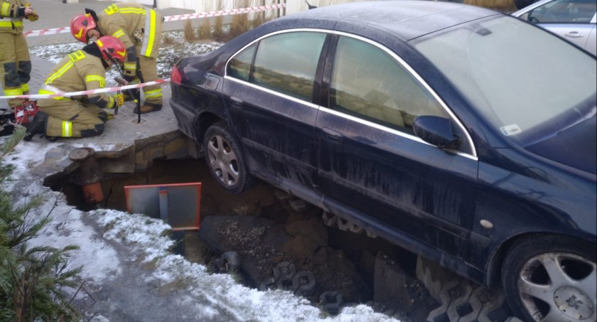 Samochód utknął w leju. Jest znana wstępna przyczyna podmycie parkingu i jezdni - Zdjęcie główne